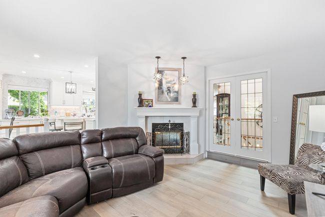 Living area with light wood-style flooring, a tiled fireplace, a chandelier, and recessed lighting | Image 19
