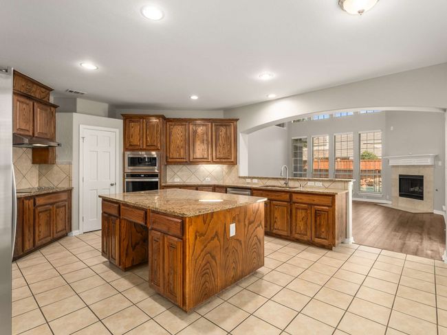 Kitchen featuring light tile patterned floors, visible vents, a kitchen island, and stainless steel appliances | Image 12
