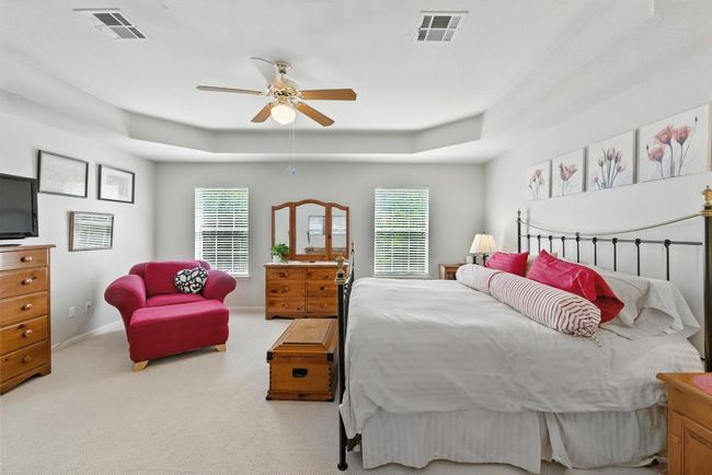Carpeted bedroom with a raised ceiling, multiple windows, and a ceiling fan | Image 18