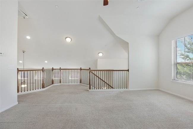 Carpeted spare room featuring lofted ceiling, baseboards, and ceiling fan | Image 16