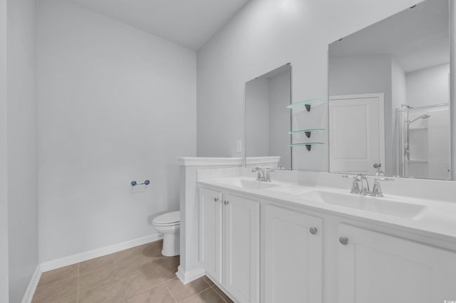 Bathroom featuring a sink, toilet, double vanity, and tile patterned floors | Image 9