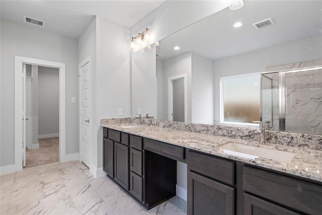 This primary bathroom is definitely move-in ready! Featuring stained wood cabinets with granite countertops, spacious walk-in closet with shelving, high ceilings, custom paint, sleek and dark modern finishes. | Image 11