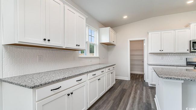 Kitchen with white cabinets, backsplash, dark hardwood / wood-style flooring, light stone countertops, and vaulted ceiling | Image 15