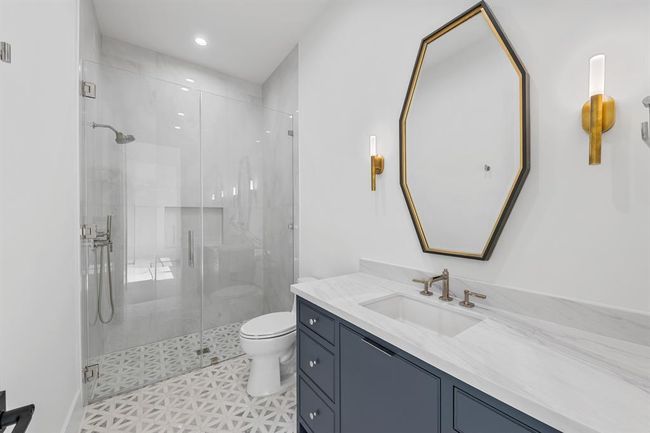 Located on the first floor for ultimate accessibility, this secondary suite blends comfort with sophisticated design. The attached bathroom features curated materials—designer tile, modern fixtures, and a frameless glass shower—offering a spa-like experience in a private, peaceful setting. | Image 25
