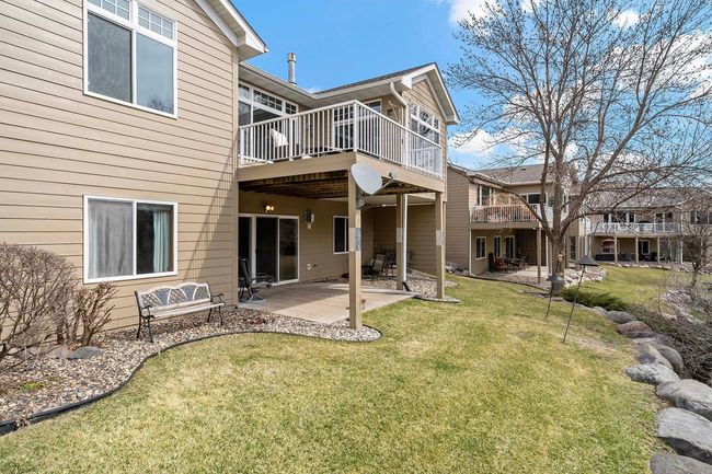 From the back of the property, a closer look at the patio and deck overlooking a retaining wall and wooded area. | Image 30