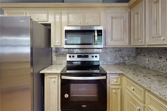 Kitchen featuring appliances with stainless steel finishes, cream cabinets, and decorative backsplash | Image 12