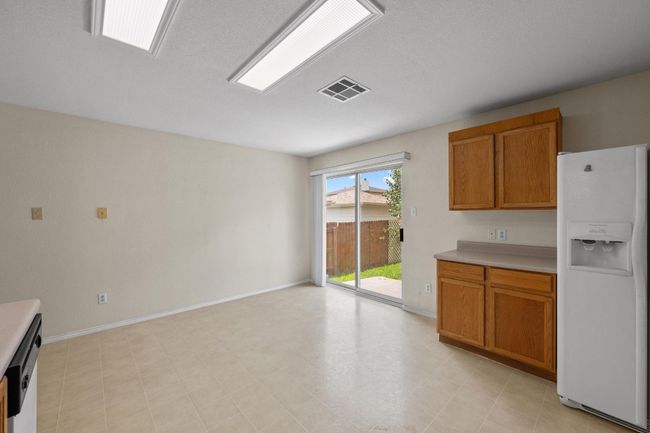 Kitchen featuring white fridge with ice dispenser, light countertops, brown cabinetry, and baseboards | Image 13