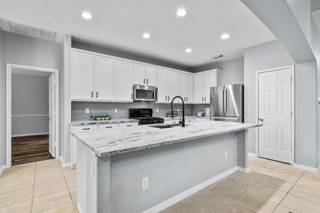 The updated kitchen features freshly painted cabinets, leathered granite counters, and upgraded hardware—bringing a crisp, cohesive look to the space. | Image 12