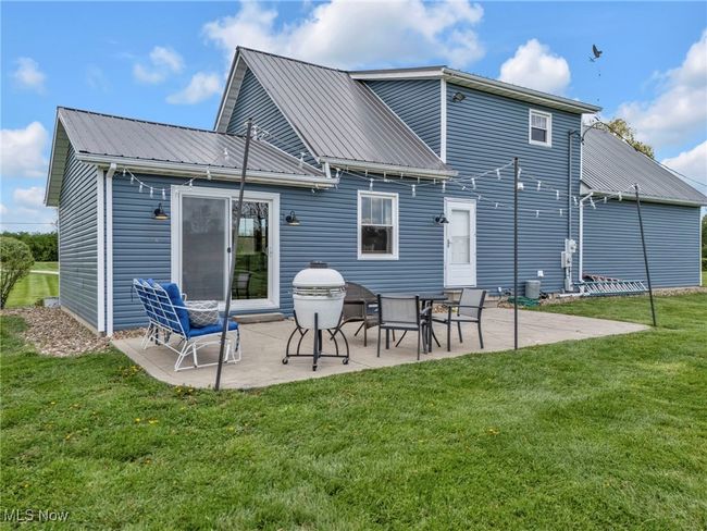 Rear view of house featuring metal roof, a lawn, and a patio area | Image 34