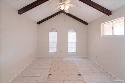 Tiled empty room with lofted ceiling with beams and ceiling fan | Image 3