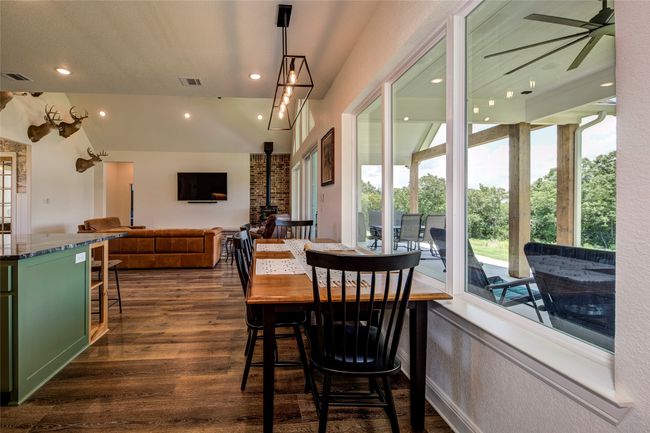 Dining space featuring a wood stove, dark hardwood / wood-style flooring, ceiling fan, and plenty of natural light | Image 23
