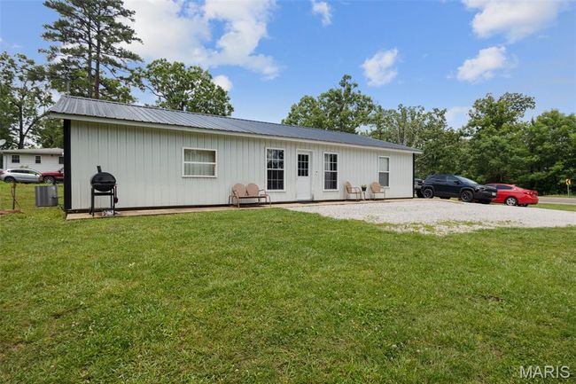 View of front facade with a front yard, metal roof, and board and batten siding | Image 24
