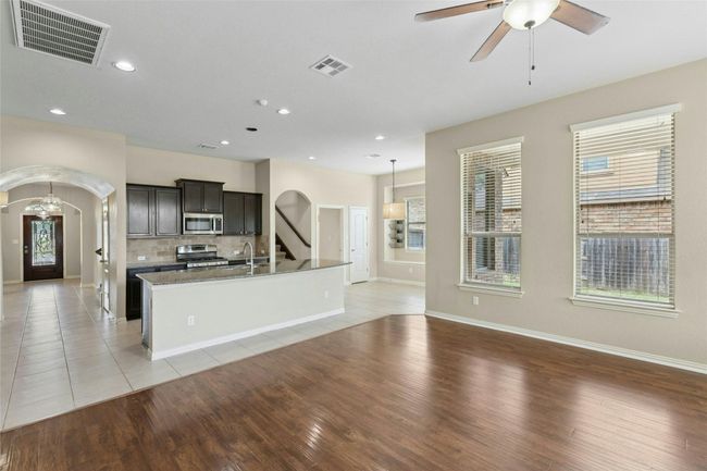 Kitchen featuring arched walkways, stainless steel appliances, a kitchen island with sink, light wood finished floors, and recessed lighting | Image 11