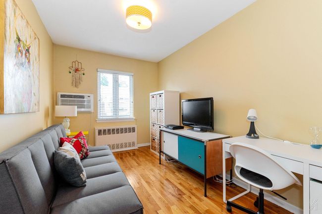 Office space featuring radiator heating unit, light wood-style flooring, an AC wall unit, and baseboards | Image 9