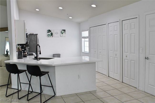 Kitchen featuring light tile patterned floors, a breakfast bar area, a peninsula, light countertops, and a sink | Image 6