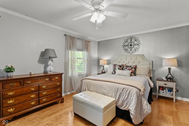 bedroom with light wood finished floors, crown molding, ceiling fan and walk-in closet. | Image 18