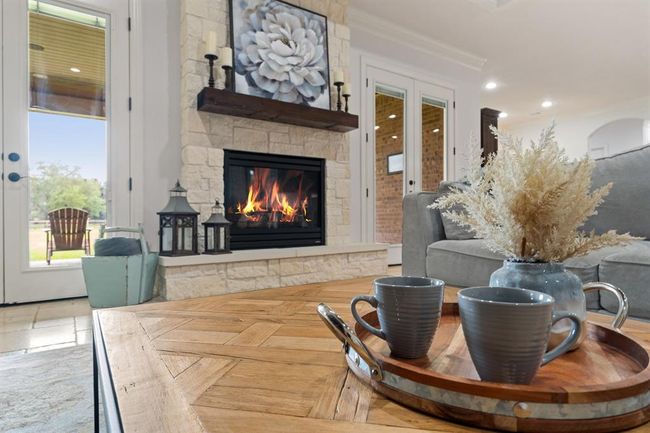 Cozy up on a chilly day by this gas fireplace, with floor to ceiling stone surround and oversized hearth. The custom wood mantle adds contrast to the fireplace, while also tying in nicely to the wood planked ceiling above. | Image 14