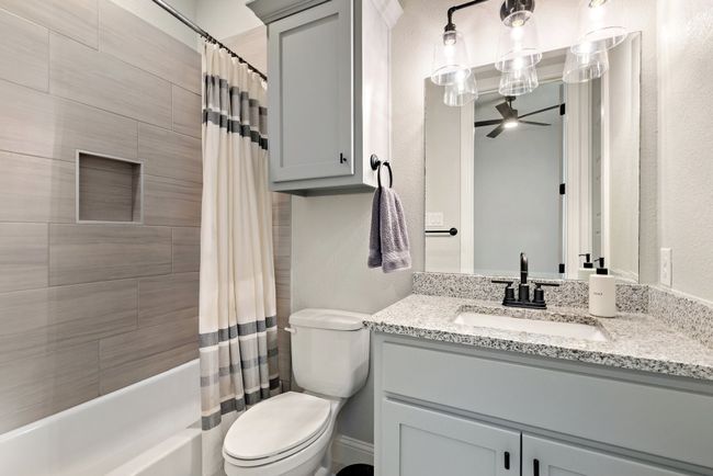 Bathroom featuring a textured wall, toilet, vanity, shower / tub combo, and ceiling fan | Image 26