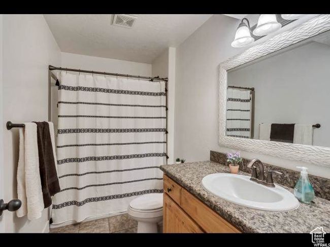 Full bath featuring vanity, toilet, a shower with curtain, and tile patterned floors | Image 8