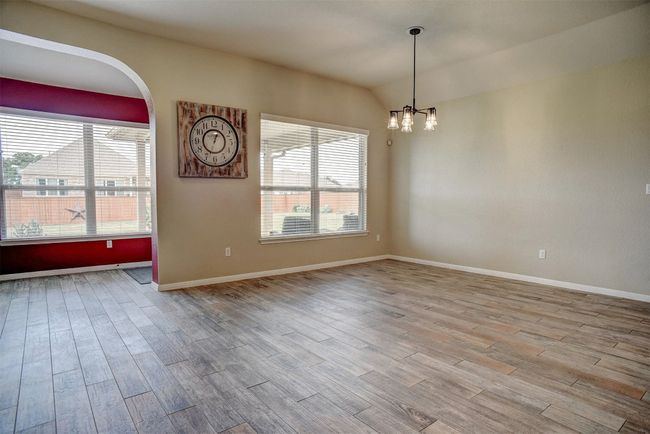 Unfurnished room featuring healthy amount of natural light, wood finished floors, a chandelier, and lofted ceiling | Image 16