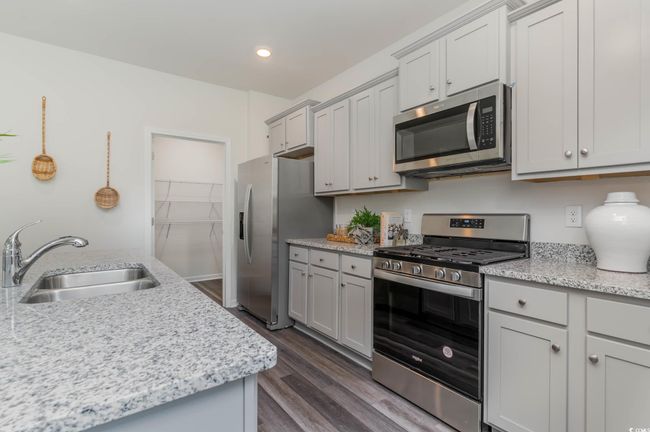 Kitchen featuring appliances with stainless steel finishes, a sink, dark wood finished floors, gray cabinetry, and recessed lighting | Image 9