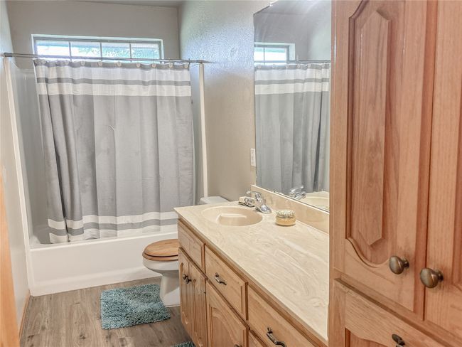 Bathroom with shower / bath combo, wood finished floors, toilet, and vanity | Image 10