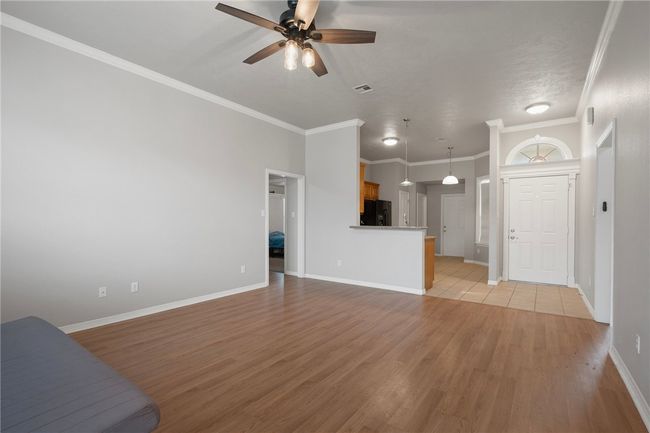 Unfurnished living room featuring a ceiling fan, light wood-style flooring, baseboards, and crown molding | Image 7