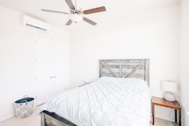 Carpeted bedroom featuring a wall unit AC, a closet, and ceiling fan | Image 9
