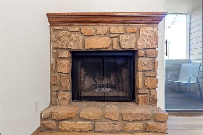 Detailed view of a stone fireplace and wood finished floors | Image 10