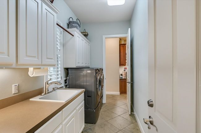 Laundry room with cabinet space, washer and dryer, deep well sink with access to the 3rd bay garage/workshop. | Image 12