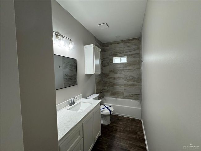 Bathroom featuring toilet, vanity, wood finished floors, and bathtub / shower combination | Image 13