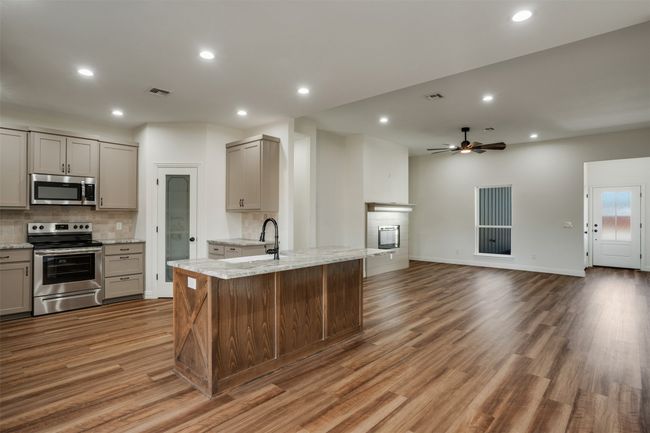Kitchen featuring light wood finished floors, stainless steel appliances, a sink, backsplash, and gray cabinets | Image 9