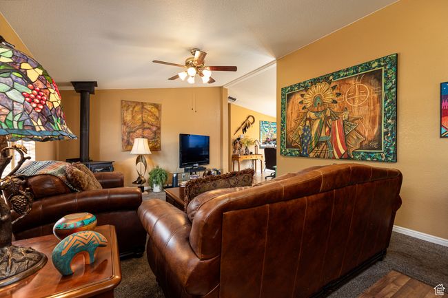 Living room featuring dark colored carpet, lofted ceiling, a wood stove, and ceiling fan | Image 5
