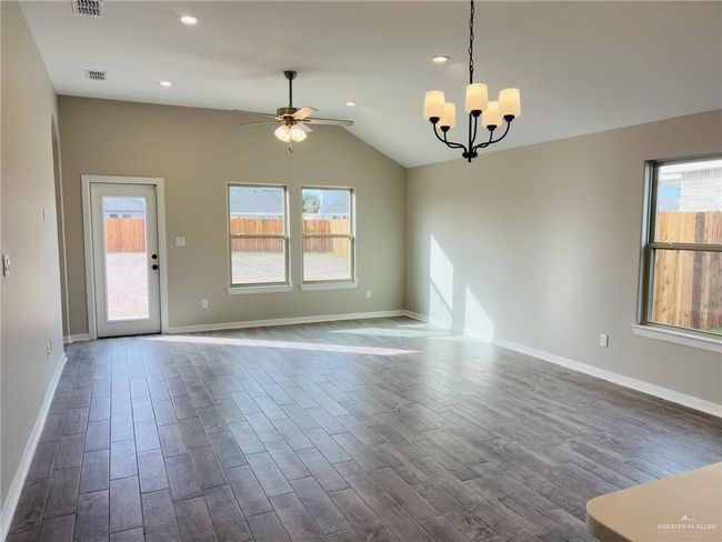 Spare room featuring hardwood / wood-style flooring, a wealth of natural light, vaulted ceiling, and ceiling fan with notable chandelier | Image 4