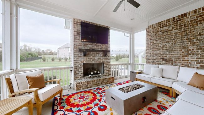 Cozy up in this screened-in porch featuring a brick fireplace, mounted TV, and ample seating—perfect for year-round entertaining or peaceful mornings with a view. A true extension of indoor comfort to the outdoors! | Image 37