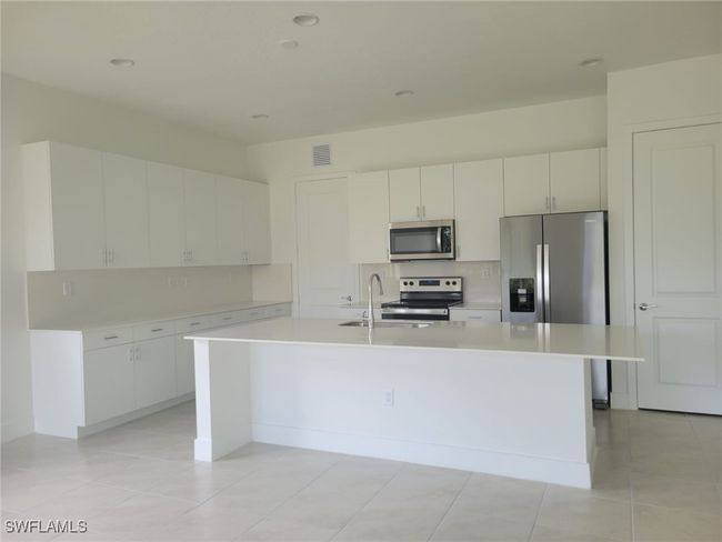Kitchen with appliances with stainless steel finishes, light countertops, tasteful backsplash, a kitchen island with sink, and recessed lighting | Image 5