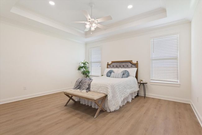Bedroom featuring a raised ceiling, crown molding, light wood-style floors, recessed lighting, and a ceiling fan | Image 14