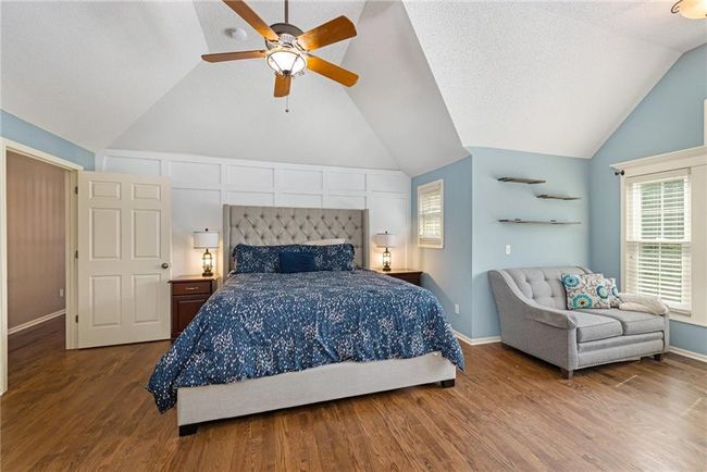 Bedroom featuring vaulted ceiling, wood finished floors, baseboards, and a ceiling fan | Image 27