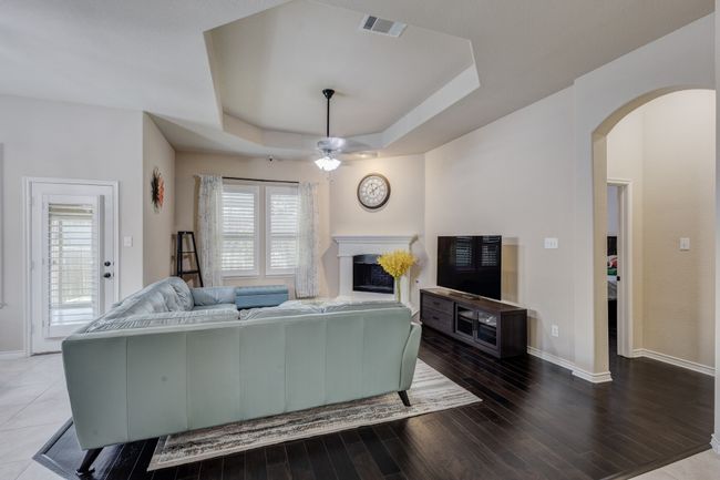 Living room featuring a fireplace, arched walkways, baseboards, ceiling fan, and wood finished floors | Image 6