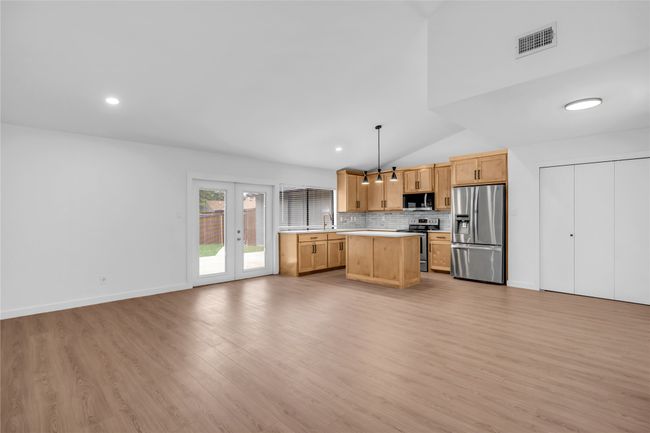 Kitchen featuring appliances with stainless steel finishes, light countertops, lofted ceiling, open floor plan, and light wood-style flooring | Image 16