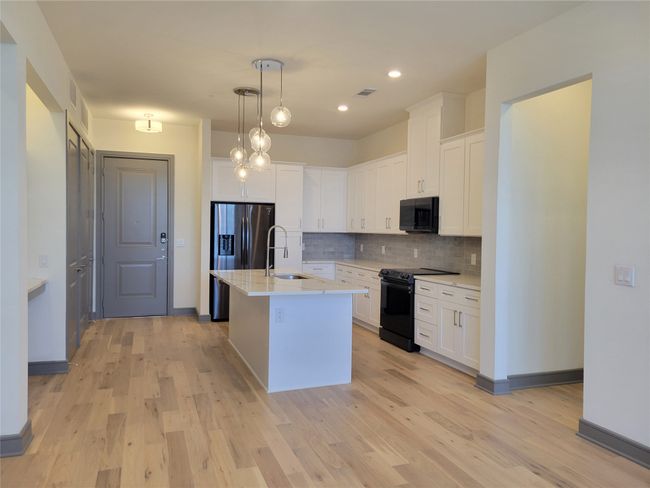 Kitchen featuring tasteful backsplash, a sink, black appliances, light wood-style flooring, and visible vents | Image 5