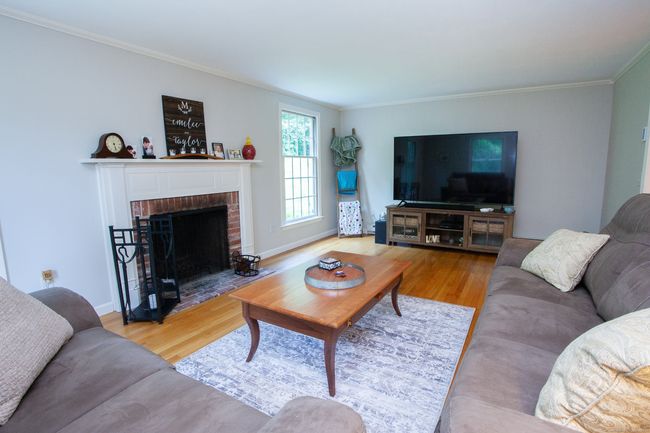Formal living room with wood burning fireplace, hardwood floors and freshly painted. | Image 14