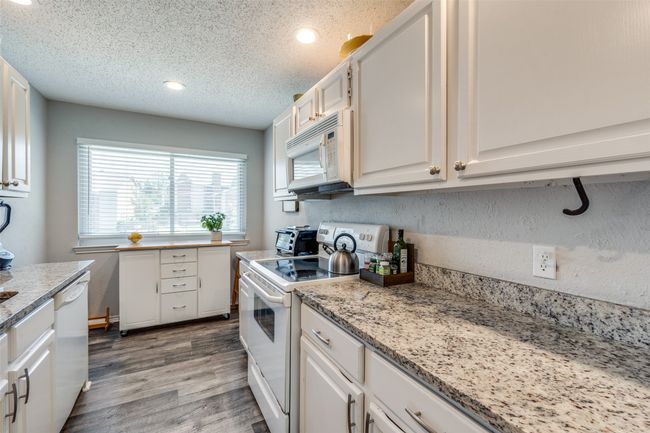 Kitchen featuring white appliances, light wood-style flooring, white cabinets, recessed lighting, and a textured ceiling | Image 8