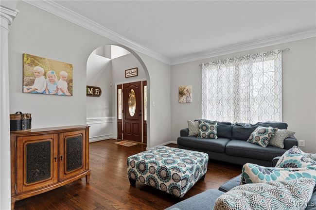 Living room featuring crown molding, dark wood-style floors, arched walkways, and wainscoting | Image 22