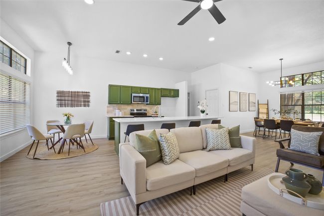 Living area featuring light wood-style floors, a chandelier, ceiling fan, recessed lighting, and a towering ceiling | Image 8