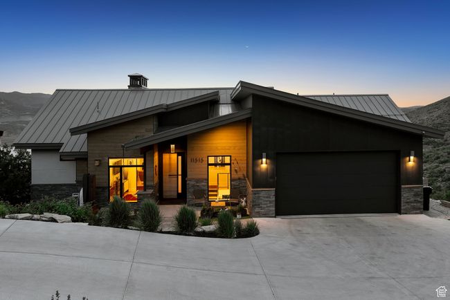 Modern home featuring a standing seam roof, an attached garage, concrete driveway, a metal roof, and stone siding | Image 95