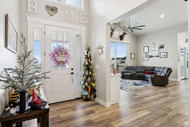 Foyer entrance featuring light wood finished floors, ceiling fan, a towering ceiling, and baseboards | Image 55