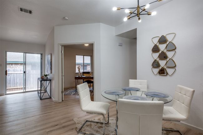 Dining space featuring an inviting chandelier, vaulted ceiling, visible vents, wood finished floors, and baseboards | Image 14