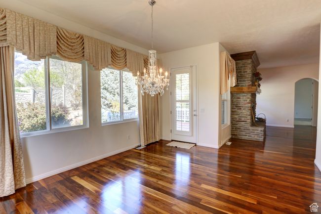 Unfurnished dining area with arched walkways, a notable chandelier, baseboards, and wood finished floors | Image 24