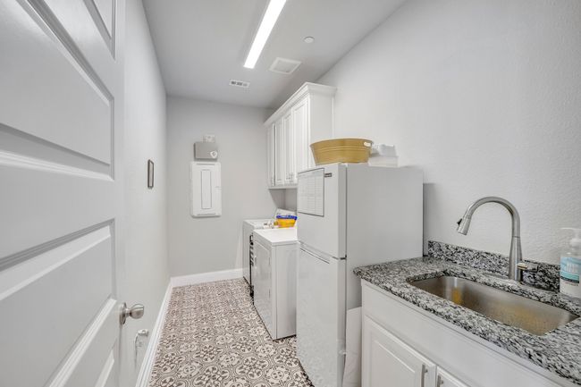 Laundry room featuring cabinets, light tile patterned floors, washing machine and dryer, and sink | Image 11